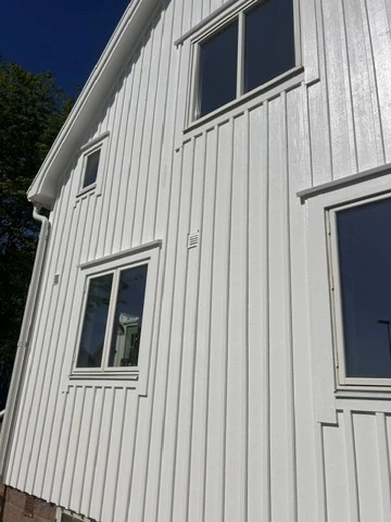Renoverad fasad i vit stående träpanel på Bohus-Malmön-villan