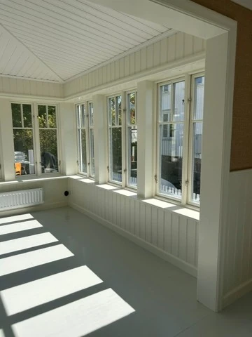 Ljust rum med fönsterrad och solspel på golvet