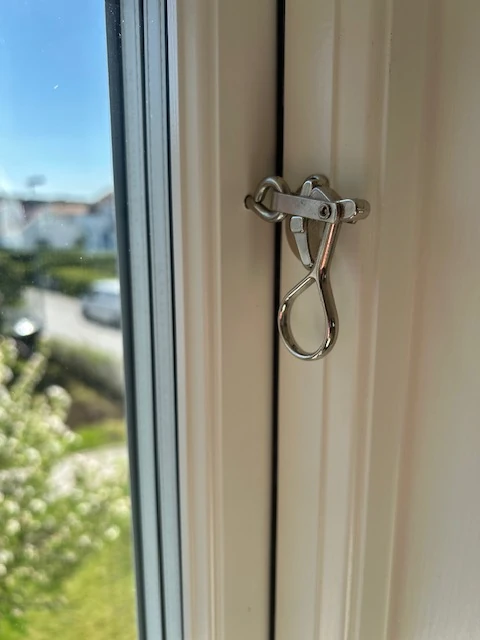 Närbild på blank fönsterhandtag i metall med utsikt mot gatan
