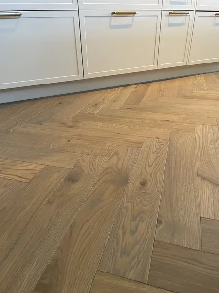 Fiskbensgolv i ek från S-golv intill ljusgrå luckor i Ballingslöv-stil
